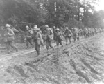 Japanese-American infantrymen of US 442nd Regimental Combat Team hike up a muddy French road in the Chambois Sector, France, late 1944