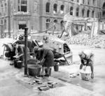 German women doing their washing at a cold water hydrant on the street in Berlin, Germany, 3 Jul 1945; note the knocked out German SdKfz. 223 vehicle in background