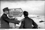 Two German soldiers before a festive sign in German directing them to 