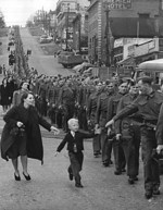 Canadian boy chasing after his father, a member of the Canadian Army British Columbia Regiment, who was on march in New Westminster, British Columbia, Canada, 1 Oct 1940