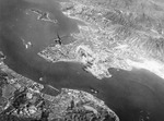 Smoke rising from Kowloon, Hong Kong, 16 Oct 1944; note Japanese fighter chasing the USAAF bomber from which this photo was taken