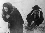 Old Russian woman pulling a man on a sled, Leningrad, Russia, date unknown