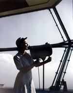 WAVES Specialist 2nd Class Jane Rockman using a control tower signal lamp to flash landing instructions to an incoming plane, Naval Air Station, Norfolk, Virginia, United States, circa 1943-1945