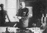 Adam Czerniaków in his office in the Warsaw ghetto, Poland, 1939-1942; note German officer in background