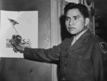 Ira Hayes with a photograph of the second flag raising on Iwo Jima, Japan, date unknown