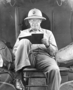 General Thomas Holcomb reading a book during a flight on a PBY Catalina between unknown Pacific Islands, circa 1943