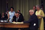 US President Johnson signing Medicare Bill, Independence, Missouri, US with Truman in attendance, 30 Jul 1965; also Senator Long, Mrs. Johnson, Senator Mansfield, Vice President Humphrey, Mrs. Truman