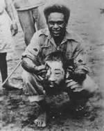 Jacob Vouza holding the severed head of a Japanese soldier, Henderson Field, Guadalcanal, Dec 1942