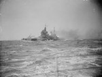 HMS Howe firing 2-pounder anti-aircraft guns while at sea in the Atlantic Ocean, 1942-1943; HMS Berwick in background; photo taken from HMS King George V