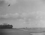 US Navy LST-134 beached at Normandy, France while unloading during low tide, 12 Jun 1944; note barrage balloons overhead providing protection from air attack and DUCKs on the beach