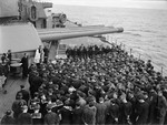 Sailors of HMS Rodney holding a religious service in remembrance of those lost aboard armed merchant cruiser HMS Jervis Bay, Nov-Dec 1940