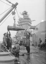 Sailors aboard HMS Rodney receiving a 16-inch shell from an ammunition ship, 1940, photo 1 of 2