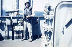 Lieutenant Rudy Holmes standing by a telescope on the bridge of Sanborn, circa 1945