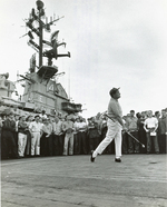American entertainer Bob Hope hitting a golf ball off of the flight deck of USS Ticonderoga, off Vietnam, 26 Dec 1965