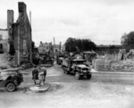 Convoy of US CCKW 2 1/2-ton 6x6 transport trucks moving inland after heavy equipment cleared the road, Normandy, France, 1944; note Jeeps and heavy earth moving equipment