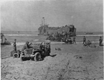 LST unloading vehicles and supplies on the beach in Gela, Sicily, Italy, Jul 1943; note Ford GPW Jeep in foreground