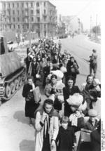 Polish civilians filing through a street in Warsaw, Poland, Aug 1944, photo 2 of 2; note Marder II tank destroyer on left