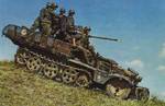 A German SdKfz. 10 halftrack vehicle mounting a 20-mm anti-aircraft gun driving down a hill with its crew aboard, date unknown