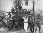 A French woman accused of being a German sympathizer being marched past an American Sherman medium tank, near Pre-en-Pail, Normandy, France, Aug-Sep 1944