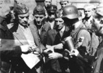 Capitan Cyprian Odorkiewicz (second from left) inspecting ammunition for PIAT launcher of Rafalki unit of resistane fighters, Okolnik gardens, Warsaw, Poland, 14 Aug 1944