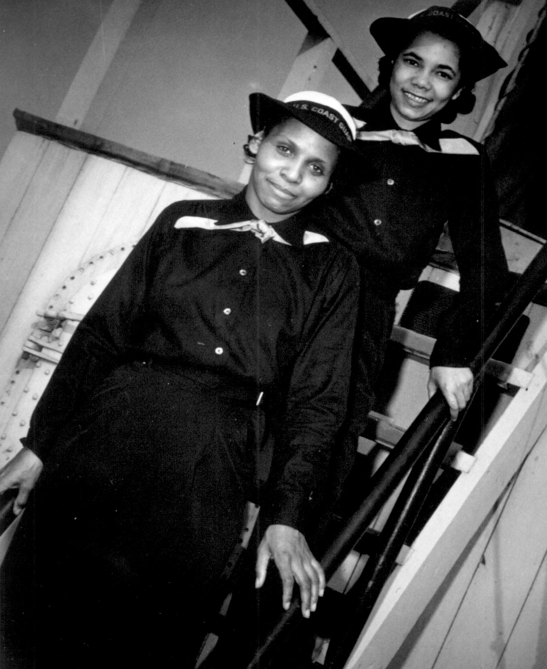 Two African-American USCG SPARS, Olivia Hooker and Aileen Anita Cooks, posing on a ladder aboard training ship 'USS Neversail', Manhattan Beach, Brooklyn, New York, United States, date unknown