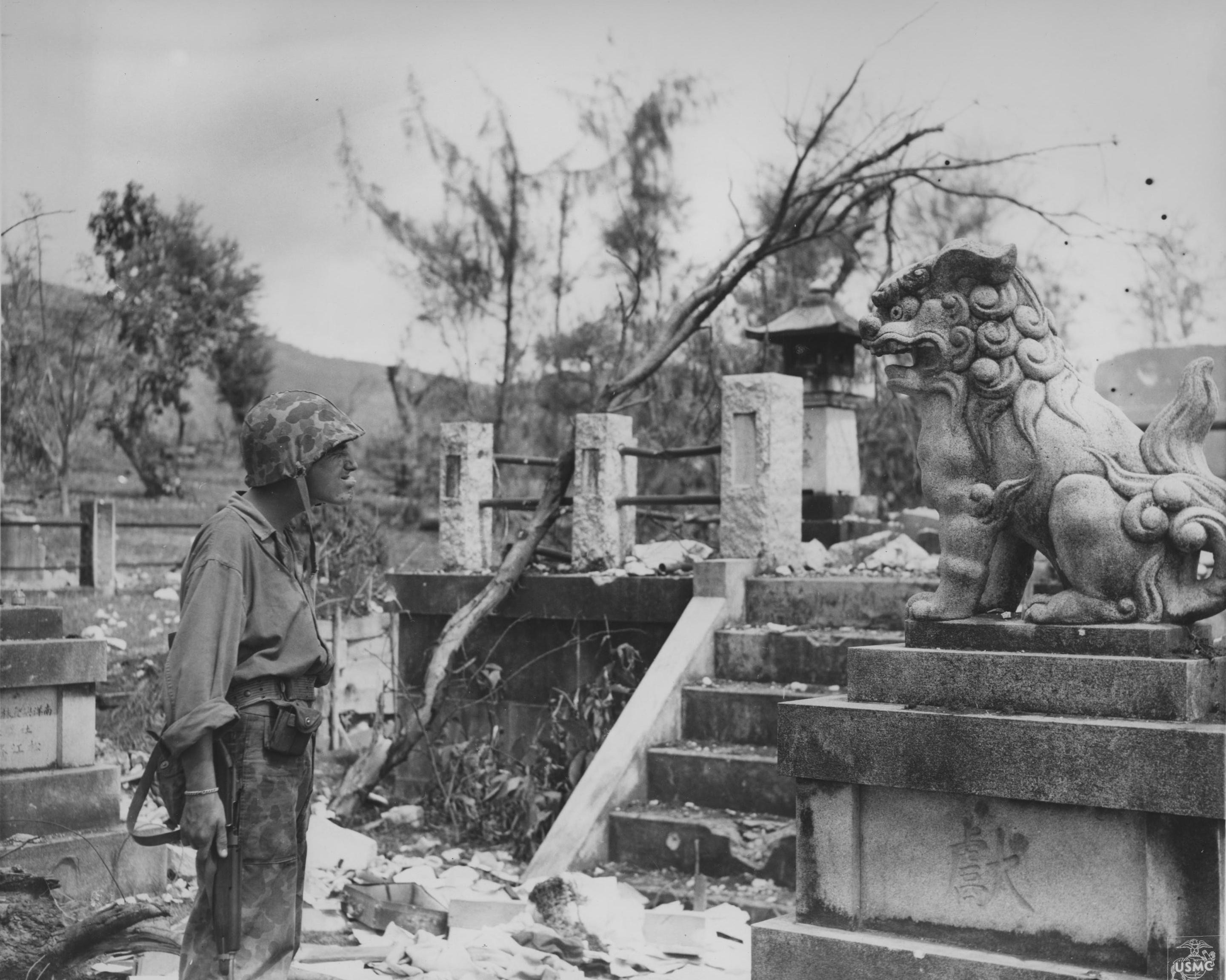 A US Marine having a moment of relaxation with a lion statue, Saipan, Mariana Islands, 27 Jul 1944