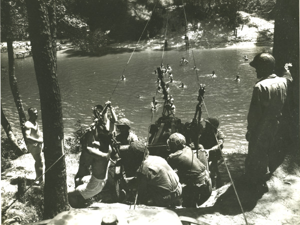 Japanese-American recruits of anti-tank company of US 442nd Regimental Combat Team ferrying a gun across a stream during training at Camp Shelby, Mississippi, United States, 6 Sep 1943