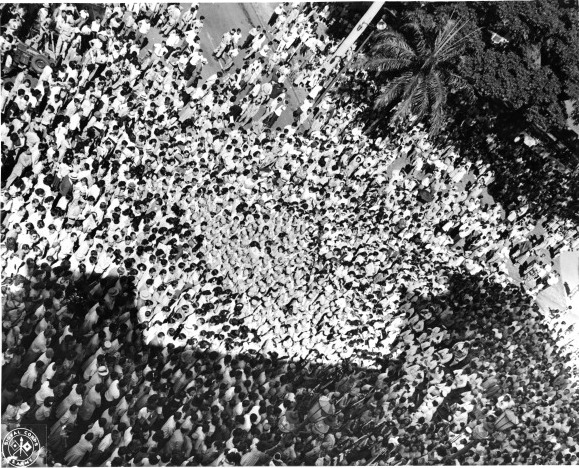 Aerial view of a crowd gathered at the Iolani Palace grounds to welcome the return of the Japanese-American troops of US 442nd Regimental Combat Team, Honolulu, US Territory of Hawaii, 9 Aug 1946