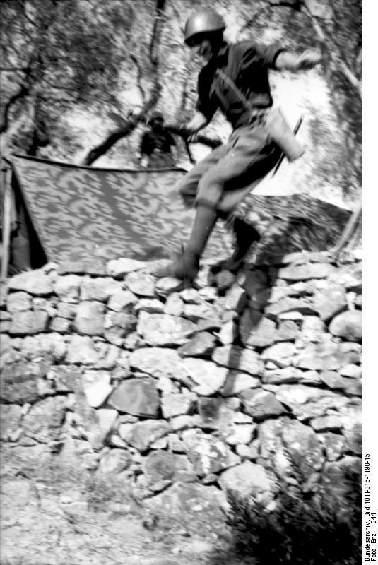 Italian Black Shirt soldier jumping over a wall with rifle with fixed bayonet, Italy, 1944