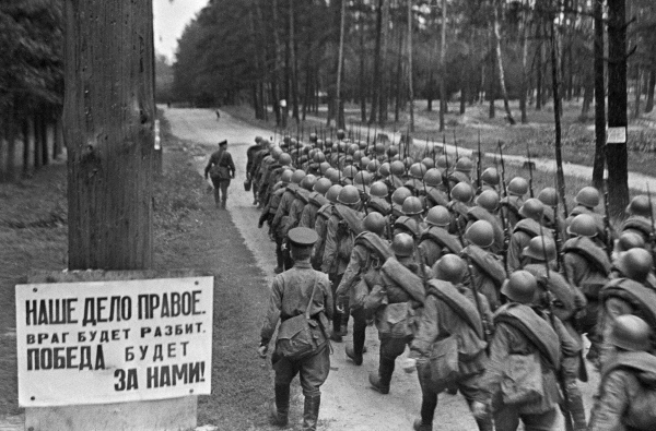 Soviet troops marching near Moscow, Russia, 23 Jun 1941; text of poster at left: 'The enemy will be defeated/Victory will be ours'