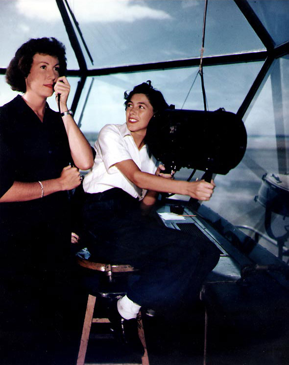 WAVES Specialist 2nd Class Mary E. Johnson directing an incoming aircraft with a microphone as Specialist 2nd Class Lois Stoneburg operated the signal lamp, Hawaiian Islands, circa mid-1945