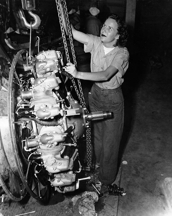 WAVES Aviation Machinist's Mate Elizabeth Abercrombie using a chain fall to lift a radial aircraft engine, at a Naval Air Station in the United States, date unknown
