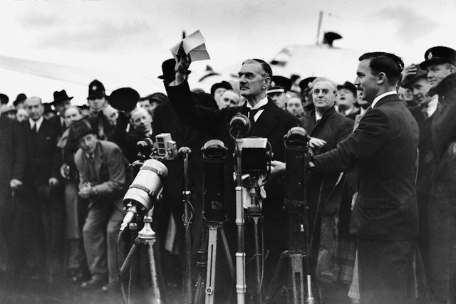 British Prime Minister Chamberlain proclaiming 'peace for our time' before the press at Heston Aerodrome near London, England, United Kingdom, 30 Sep 1938; note the Munich Agreement in his hand