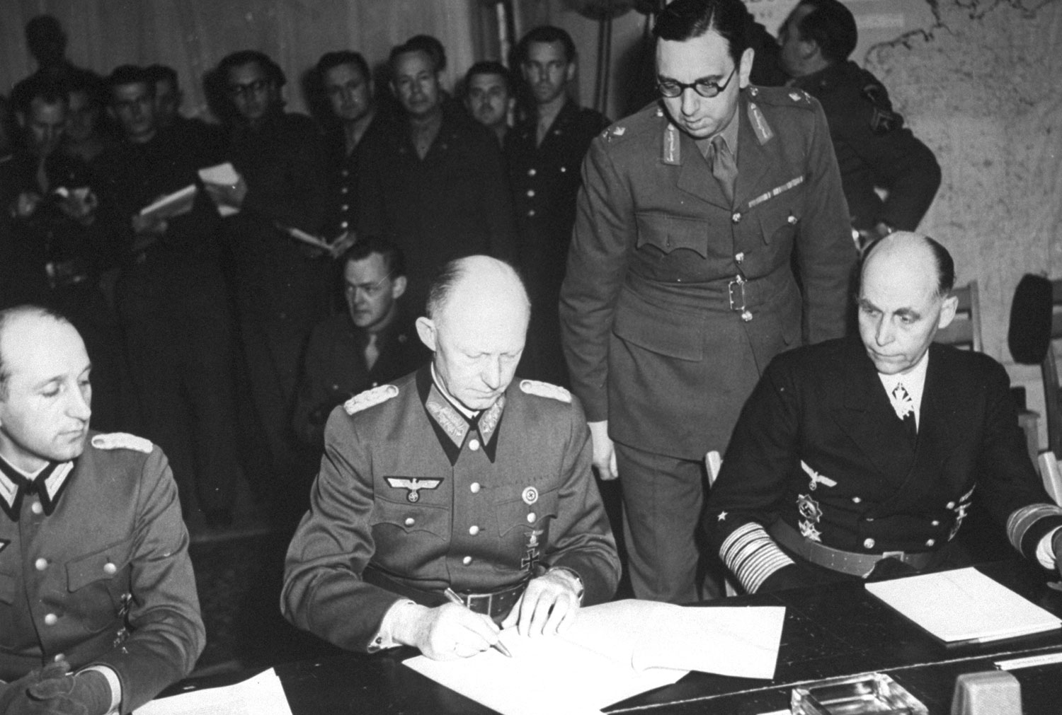 Jodl signing surrender documents at Eisenhower's headquarters, flanked by Major Wilhelm Oxenius and Admiral Hans-Georg von Friedeburg, Reims, France, 7 May 1945, photo 2 of 4