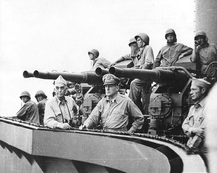 Vice Admiral Thomas Kinkaid, General Douglas MacArthur, and Colonel Lloyd Labrbas aboard cruiser Phoenix during bombardment of Los Negros Island, 28 Feb 1944; note 40-mm gun mount in background