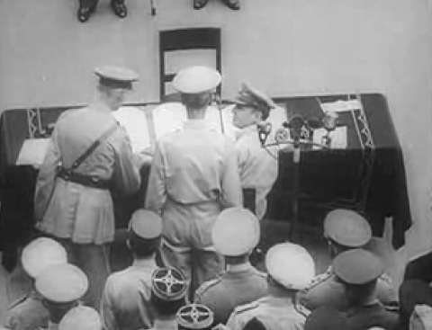 Douglas MacArthur giving a pen to Arthur Percival to sign the Japanese surrender document, aboard USS Missouri, Tokyo Bay, Japan, 2 Sep 1945