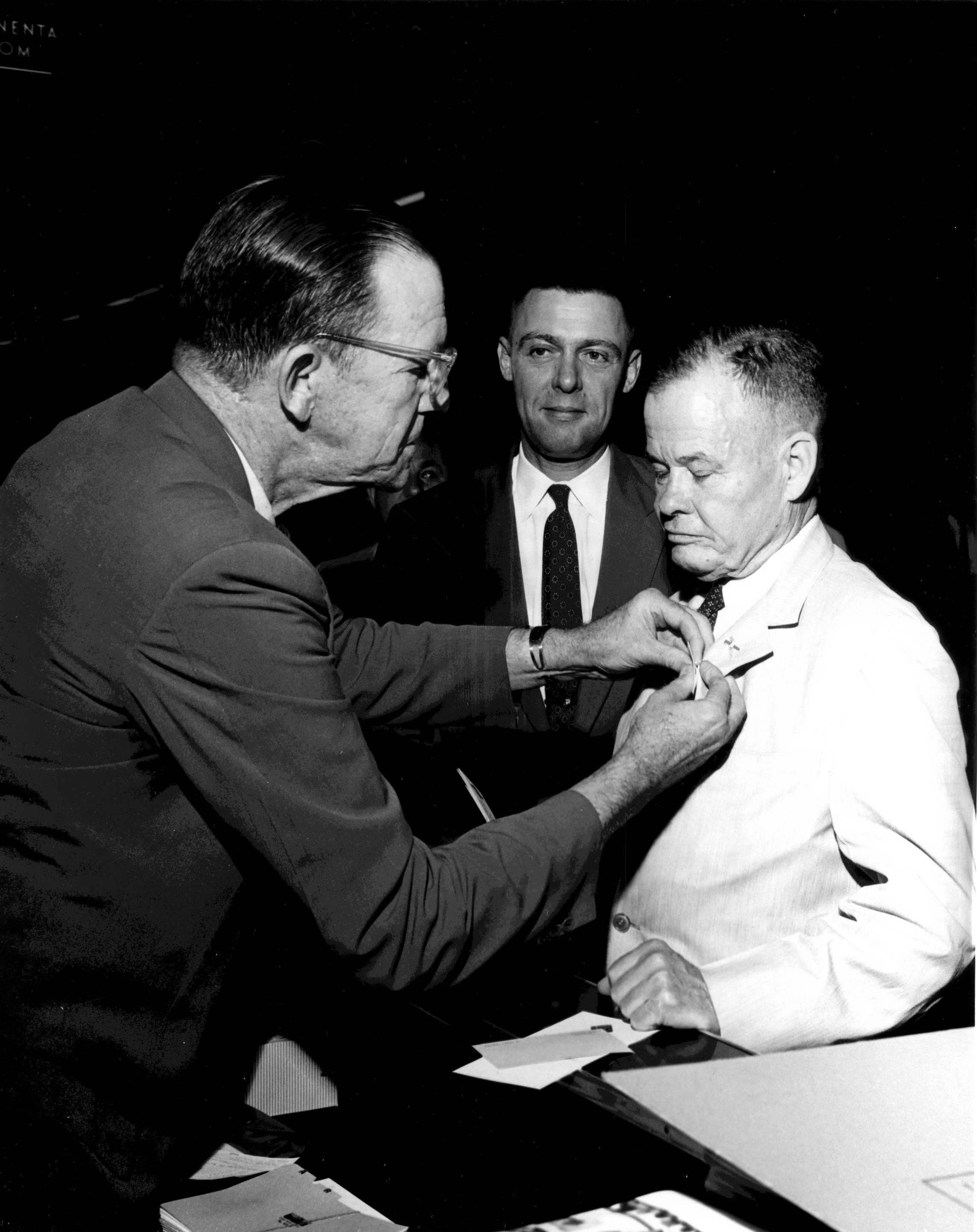 US 1st Marine Division Association Secretary-Treasurer Edwin Clarke pinning a membership card on Lieutenant General Lewis Puller, 26 Jun 1960; note Colonel Jonas Platt in background