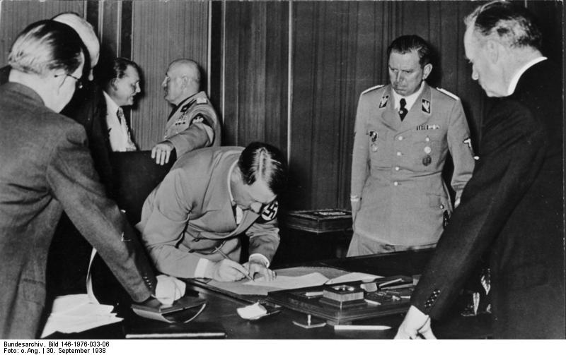 Adolf Hitler signing the Munich Agreement, Germany, 30 Sep 1938; note Joachim von RIbbentrop, Benito Mussolini, and Julius Schaub in background