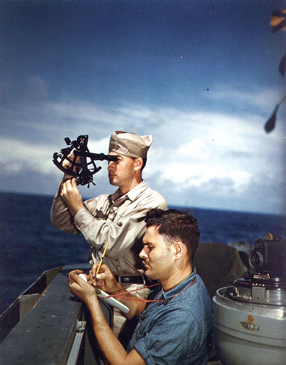 Alaska's Chief Quartermaster John P. Overholt took a sun sighting with a sextant, off Iwo Jima, 6 Mar 1945; taking notes on the observations was QM3/c Clark R. Bartholomew