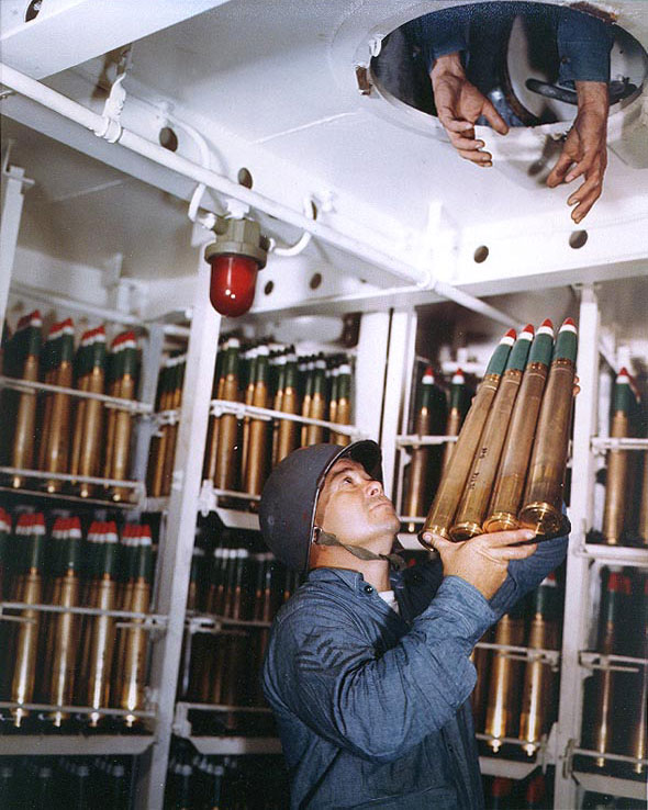 Gunner's Mate First Class Carrick N. Thomas passed a clip of four 40mm rounds through a hatch in a 40mm handling room of Alaska, off Iwo Jima, 6 Mar 1945