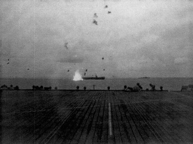 Japanese aircraft exploding near the stern of USS Corregidor, off Saipan, Mariana Islands, 17 Jun 1944; seen from the flight deck of USS Coral Sea