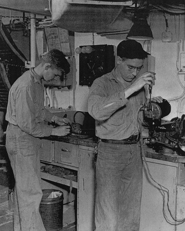 Electrician's Mate 1st Class Reichman and Electrician's Mate 3rd Class Schneider repairing electric fans aboard USS Anzio, 12 Apr 1945