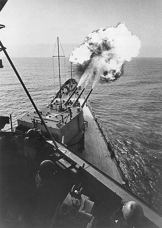 USS Canberra bombarding the coast of Vietnam, Mar 1967; note projectiles visible to the upper right of photograph