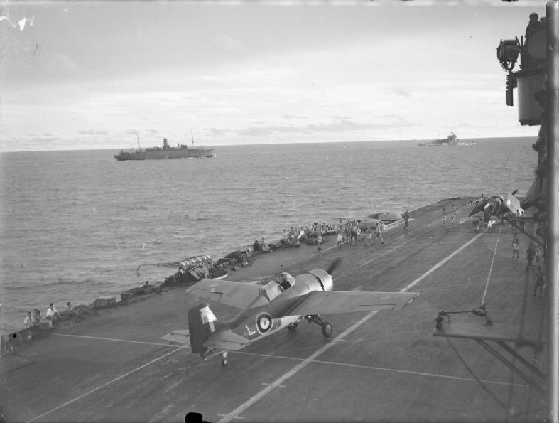 Grumman Martlet of 888 Squadron of British Fleet Air Arm taxiing on HMS Formidable after landing, circa 24 Apr-10 May 1942; HMS Warspite and AMC Alaunia in background