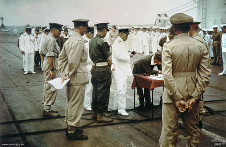 Lieutenant General Hitoshi Imamura signing the surrender document aboard HMS Glory off Rabaul, New Britain, 6 Sep 1945; Vice Admiral Junichi Kusaka and Lieutenant General Vernon Sturdee were also present