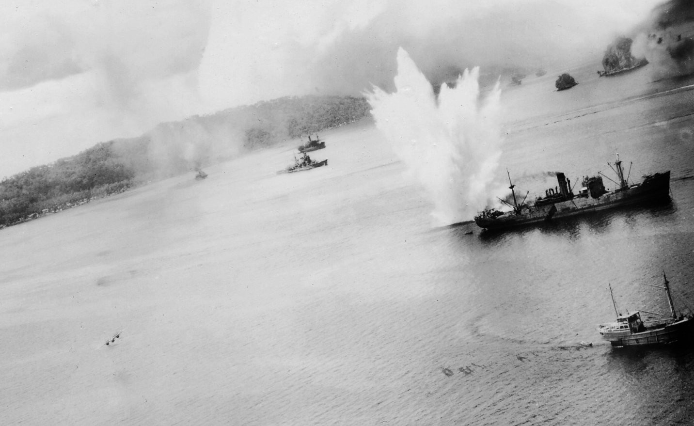 A bomb exploding off port quarter of a Japanese cargo ship in Simpson Harbor, Rabaul, New Britain, 2 Nov 1943; note Haguro in center distance and USAAF 3rd Bomb Group B-25 bomber in lower left; photo 1 of 2