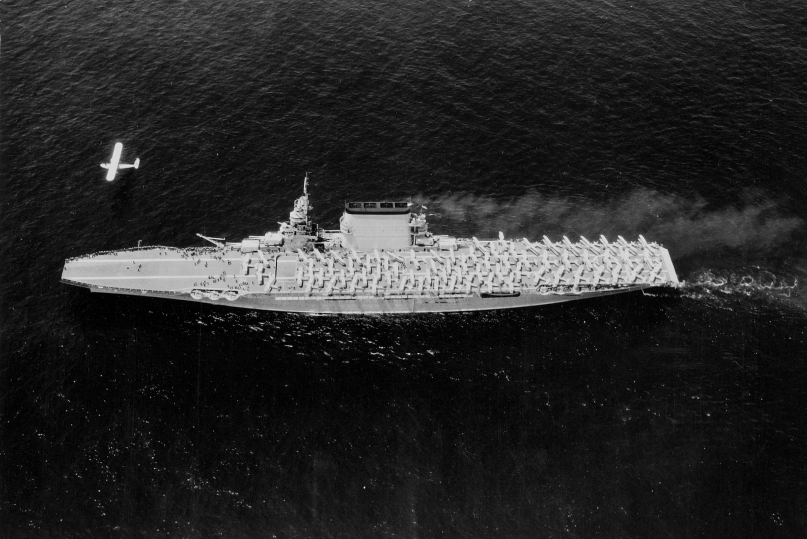USS Lexington underway, 1930; note P2Y or P3M aircraft flying above the carrier