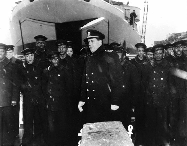 Commissioning Ceremony of Mason, Boston Navy Yard, Massachusetts, United States, 20 Mar 1944; note Lt Cmdr Blackford in center, African-American crew, and LST in background