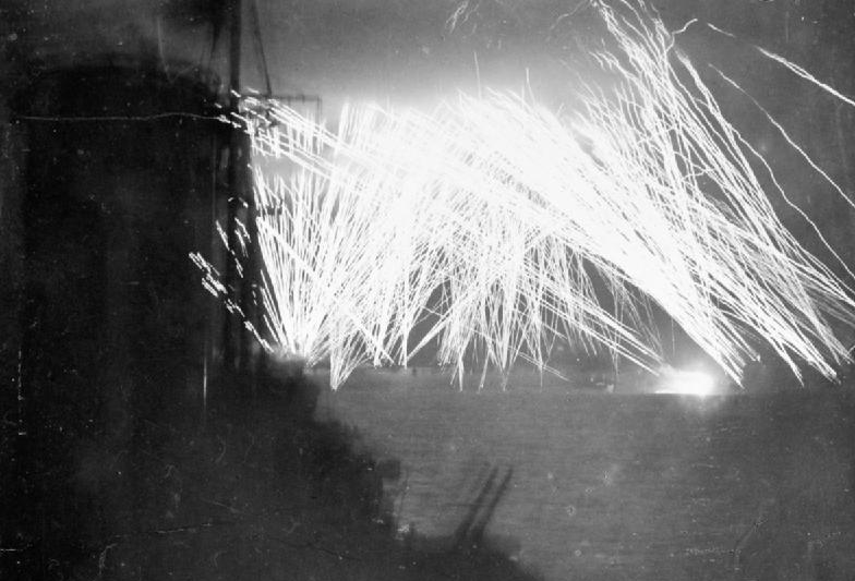 Tracer fire from Allied warships lighting up the sky off Ouistreham, France, 10 Jun 1944; photo taken from HMS Mauritius, seen in foreground