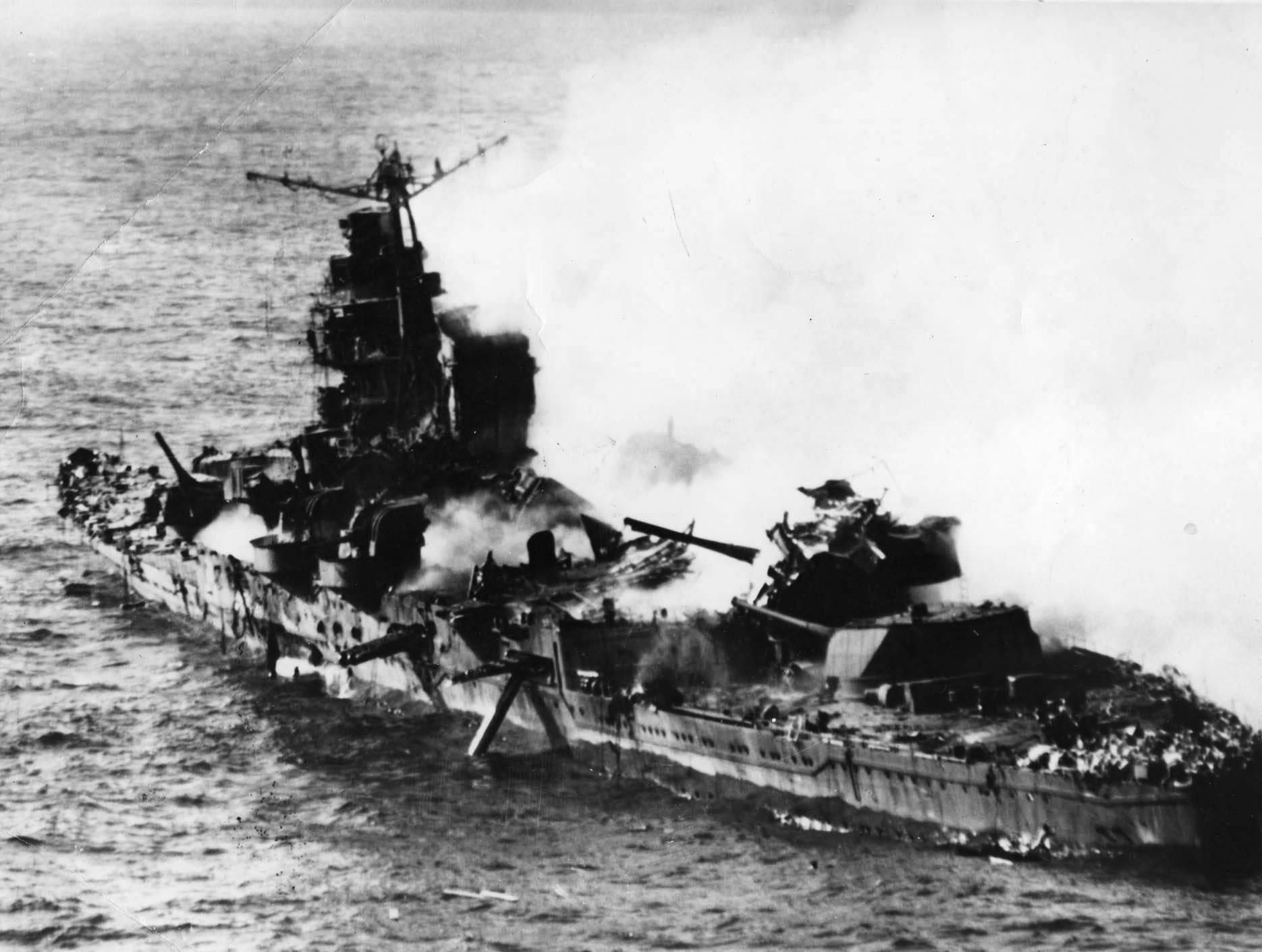 Mikuma burning, with midships structure shattered and torpedo dangling from tube, 6 Jun 1942